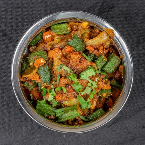 Indian Bhindi Masala, a spicy okra and onion dish, garnished with fresh cilantro in a steel bowl.