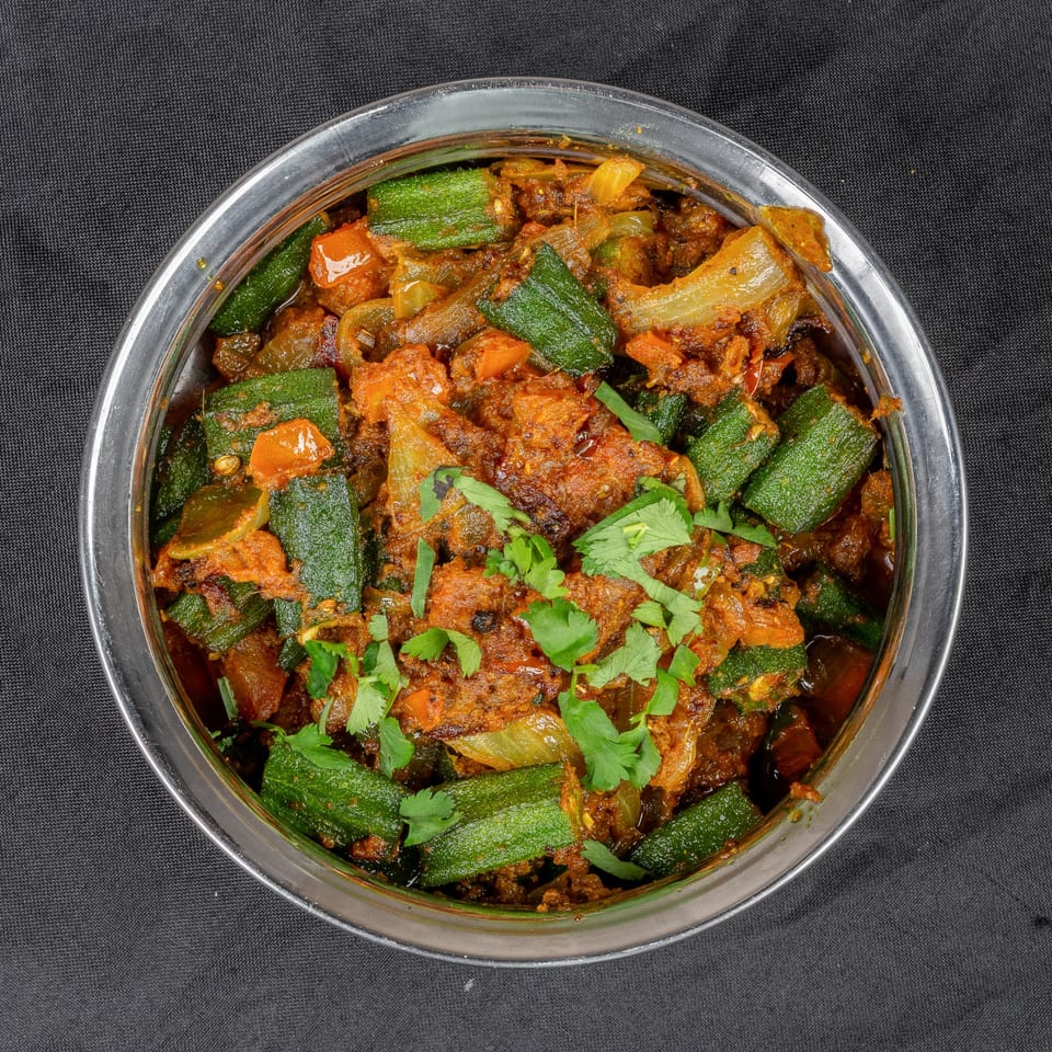 Indian Bhindi Masala, a spicy okra and onion dish, garnished with fresh cilantro in a steel bowl.